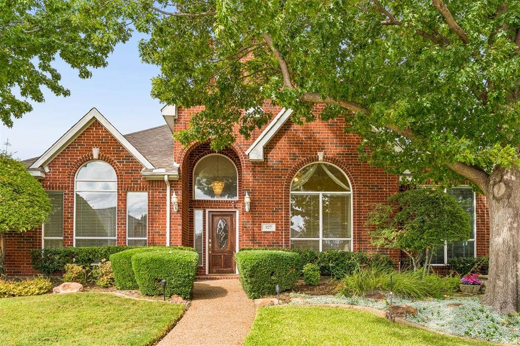 327 Hampton Court, Coppell, TX 75019 Brick exterior featuring a recessed entry, arched windows, and mature landscaping