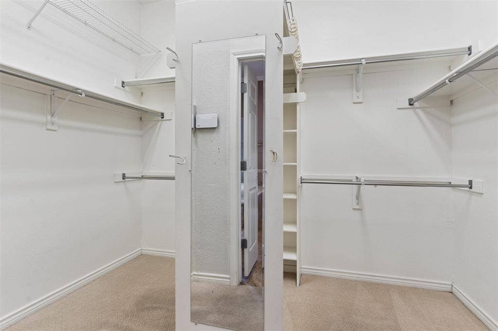 327 Hampton Court, Coppell, TX 75019 Walk-in closet featuring tiered metal garment rods, upper wire shelving, built-in vertical storage cabinetry, and a full-length wall-mounted mirror