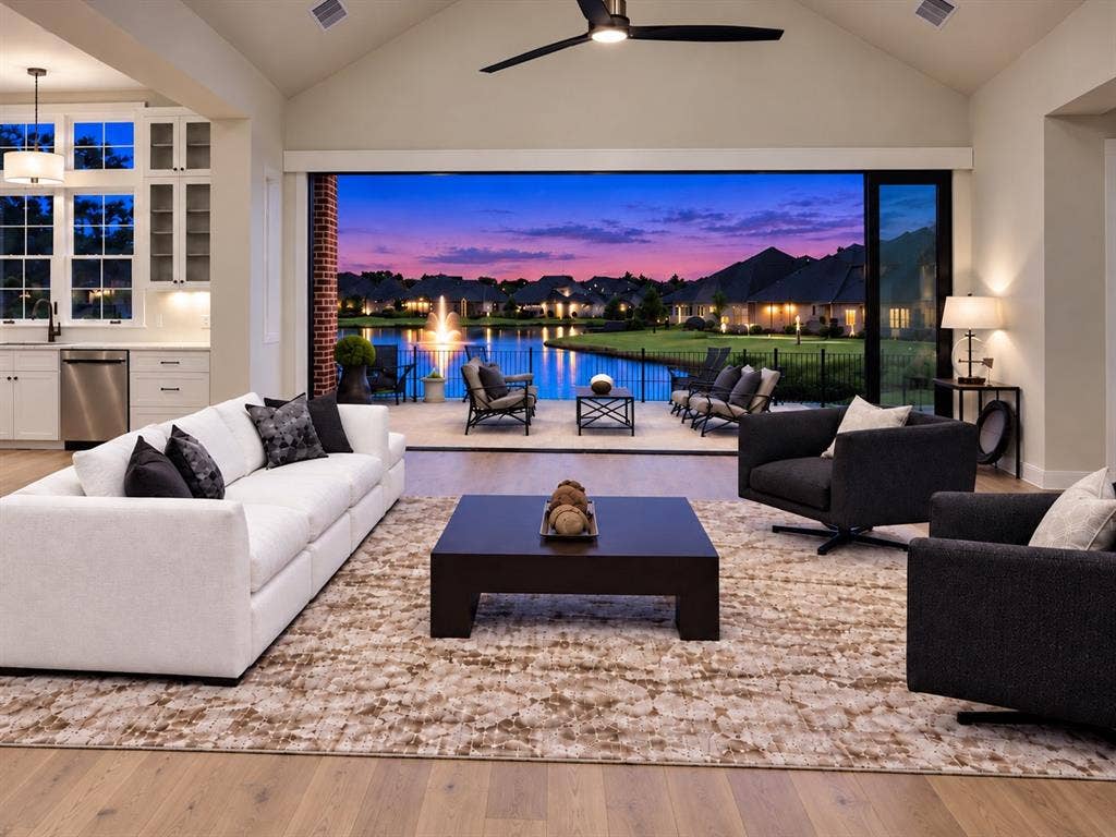 6651 Pinehurst Drive, Granbury, TX 76049 Vaulted ceiling with an installed ceiling fan, wood-finish flooring, and a full wall of sliding glass panels opening to an outdoor patio with a water feature
