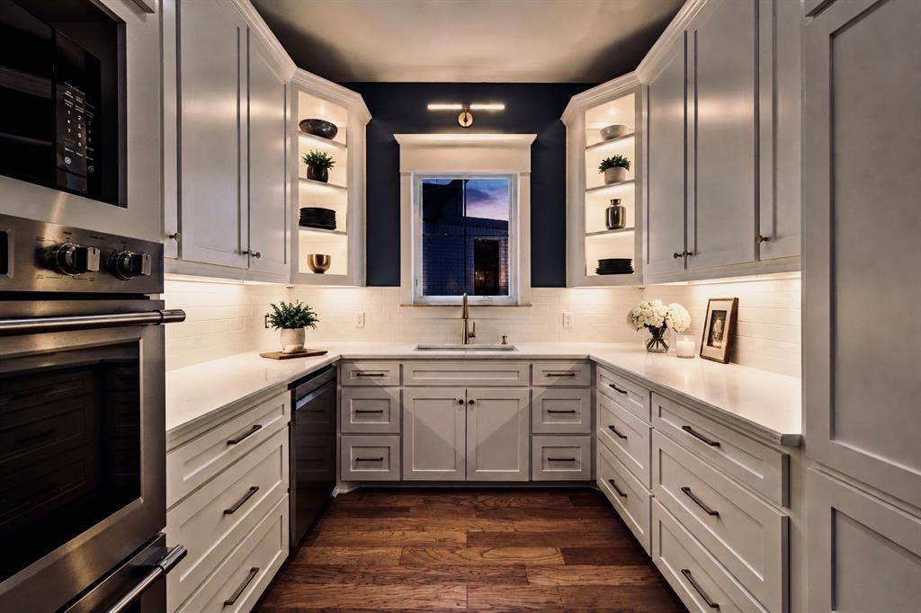 6651 Pinehurst Drive, Granbury, TX 76049 U-shaped kitchen with white shaker cabinetry, stainless steel appliances, wood-finish flooring, white subway tile backsplash, and under-cabinet lighting