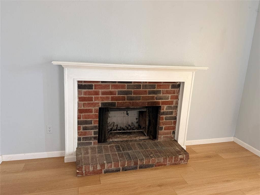 1644 Taylorcrest Drive, Dallas, TX 75253 Brick fireplace with a white mantel and hearth, complemented by wood-finish flooring
