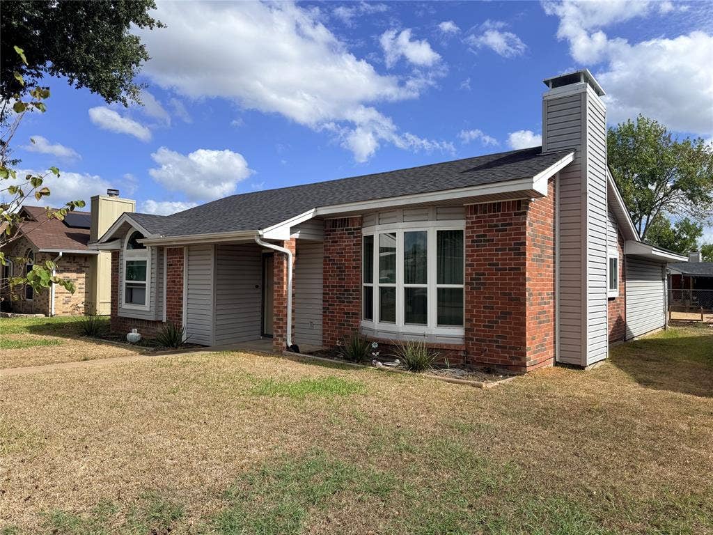 1644 Taylorcrest Drive, Dallas, TX 75253 Brick and siding exterior with a dark shingle roof, featuring a prominent bay window and a stone-clad chimney