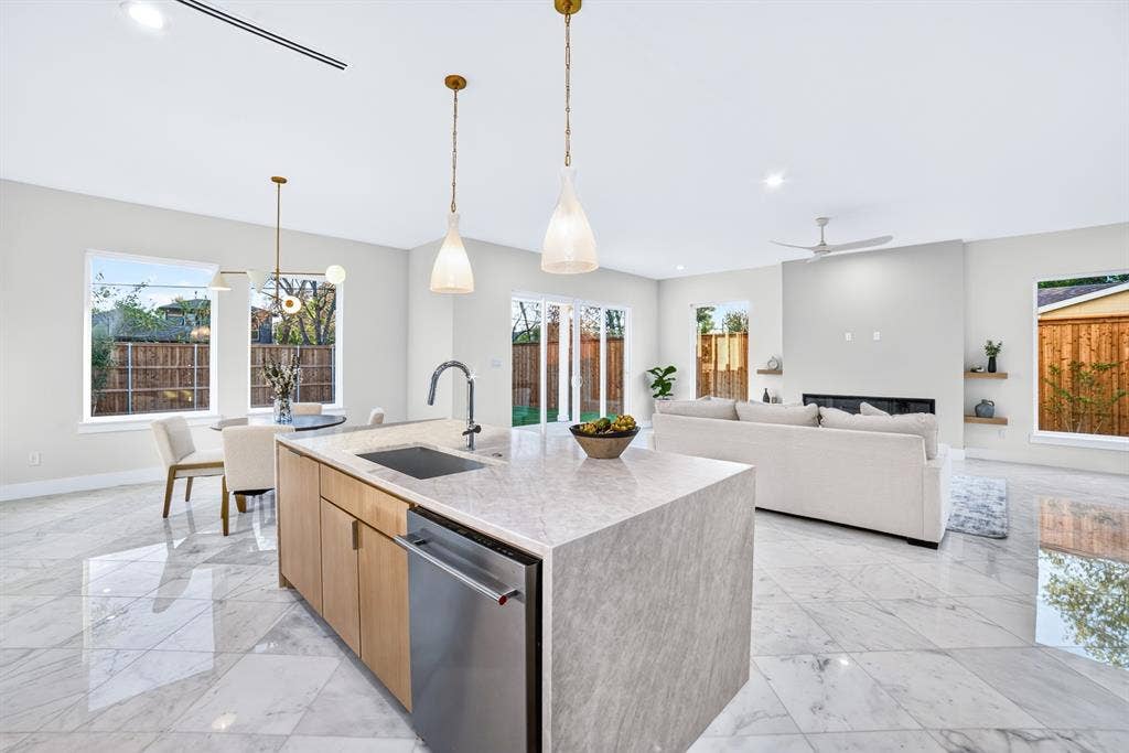 Kitchen island featuring a stone-look countertop, integrated stainless steel dishwasher, and undermount sink