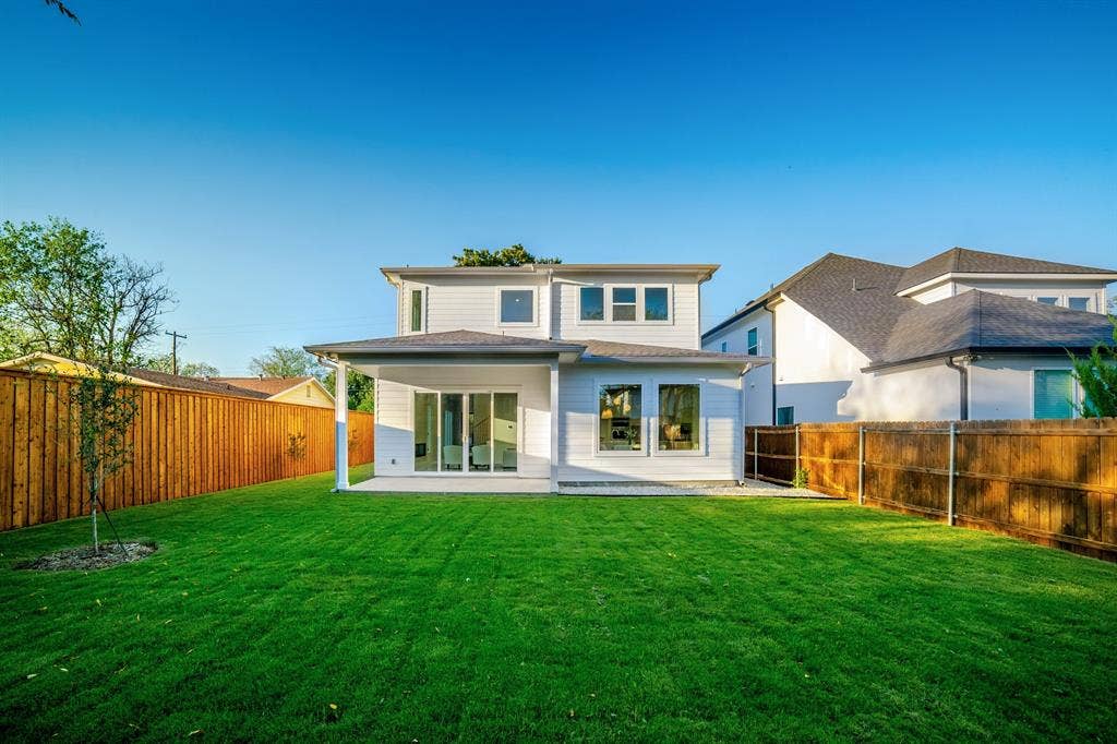 Rear exterior featuring horizontal siding, a covered concrete patio, multi-pane windows, and a fenced backyard with lawn
