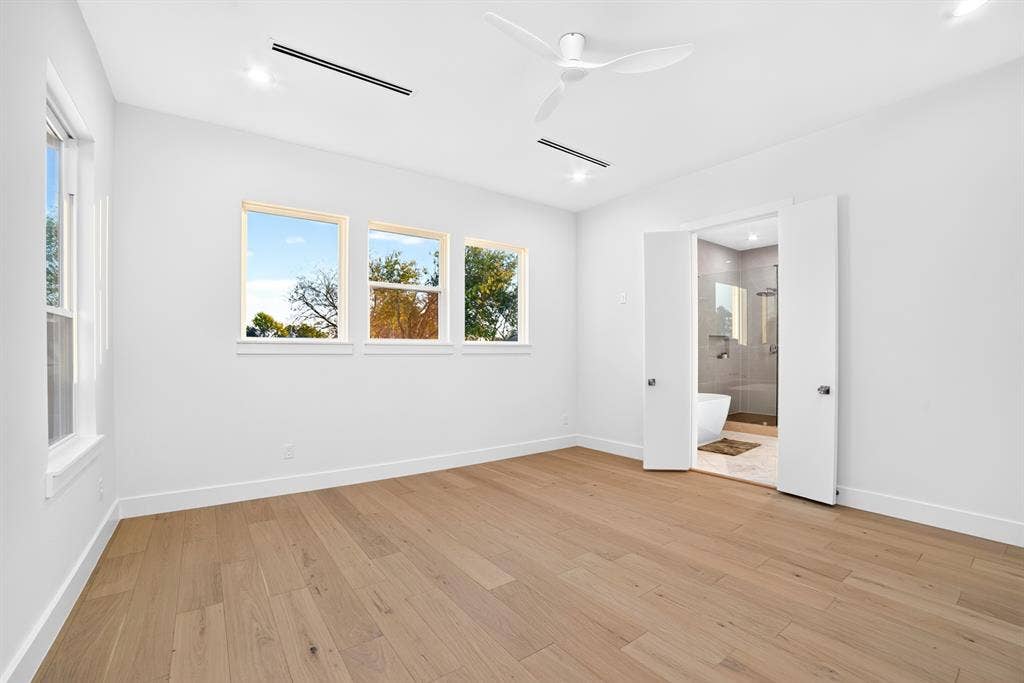 Room featuring wood-finish flooring, recessed lighting, white ceiling fan, and triple-pane window configuration