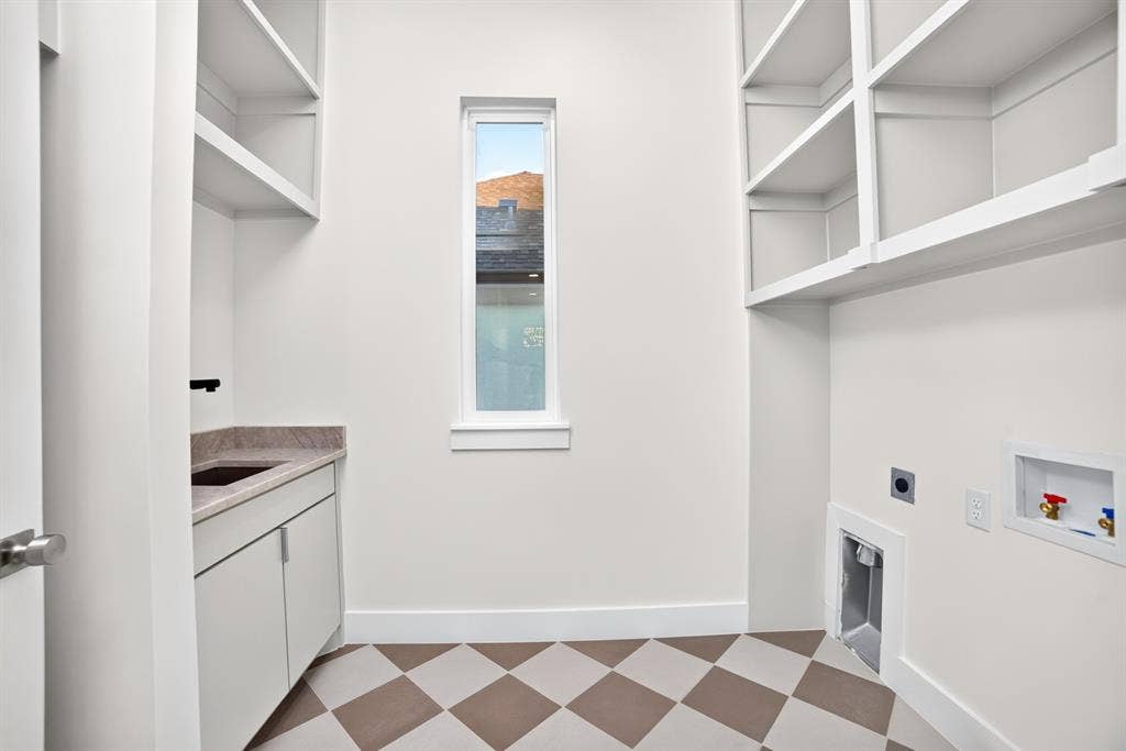 Utility room featuring custom built-in cabinetry, stone-surface countertop with integrated sink, matte black faucet, and checkerboard patterned tile flooring