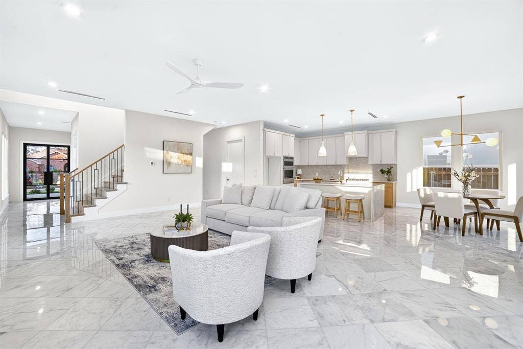 Open-concept interior featuring large-format tile flooring, a chef's kitchen with a center island and quartz countertops, recessed lighting, and a staircase with a metal railing