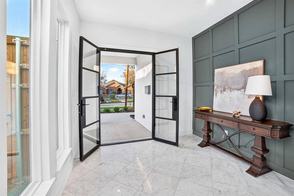 Entryway featuring a double-door glass entrance with black frames, tile flooring, and a large-scale paneled accent wall