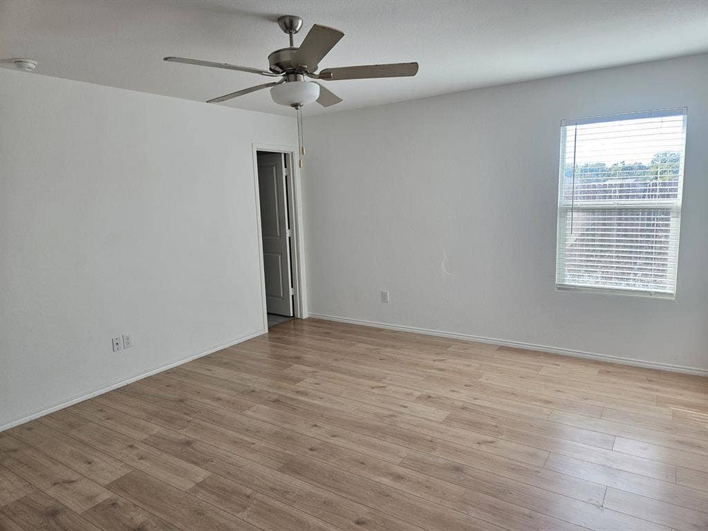 3338 Beckwith Way, Crandall, TX 75114 Wood-finish flooring with neutral wall paint, overhead ceiling fan with lighting, and a window with blinds