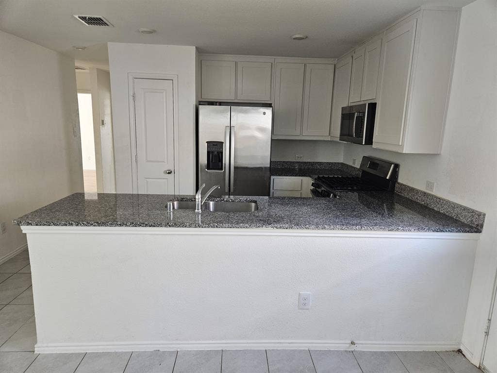 3338 Beckwith Way, Crandall, TX 75114 Granite-style countertops, stainless steel refrigerator, white cabinetry, integrated sink, and tile flooring