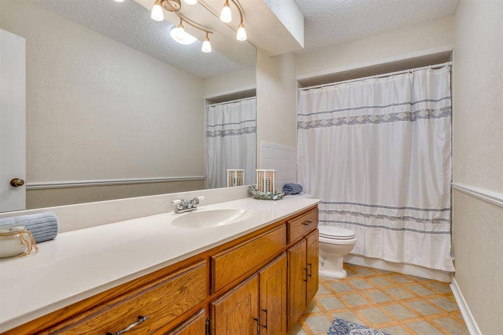 Bathroom featuring a vanity with a light-toned countertop, a built-in sink, and wood cabinetry