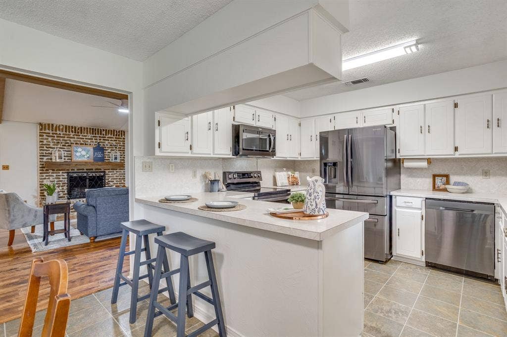 Kitchen featuring white cabinetry, stainless steel appliances, a breakfast bar, and tile flooring