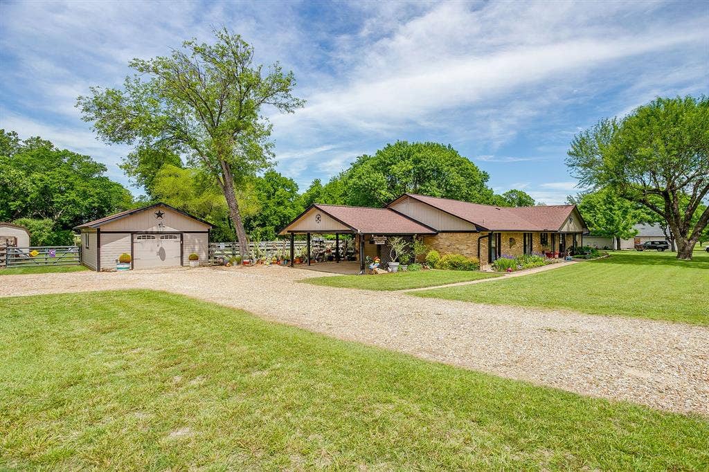 Expansive gravel driveway leading to a shop/detached garage and covered carport