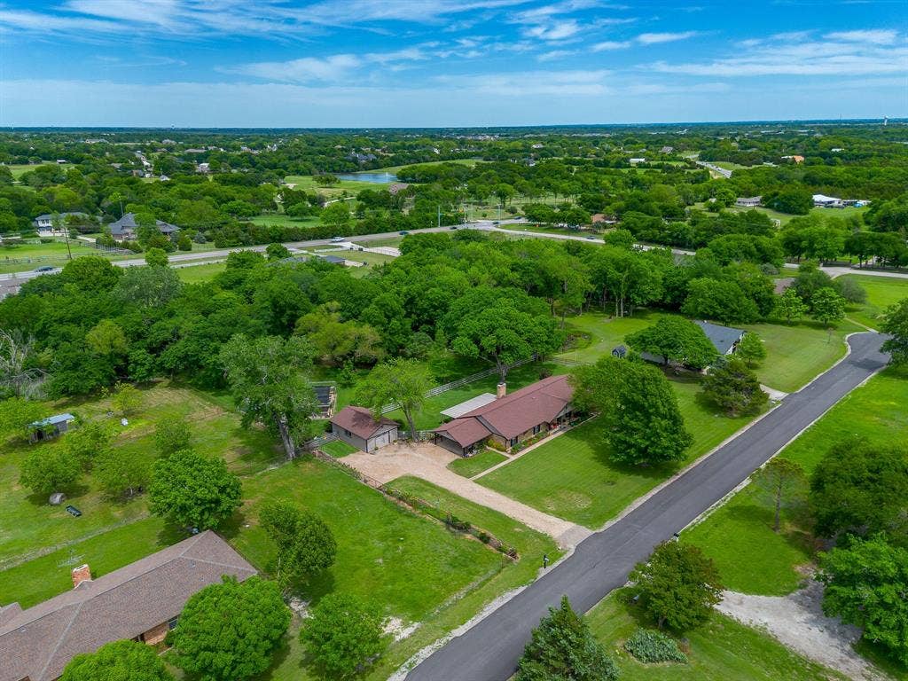 Expansive property featuring a single-story residence, detached outbuilding, paved driveway, and mature landscaping