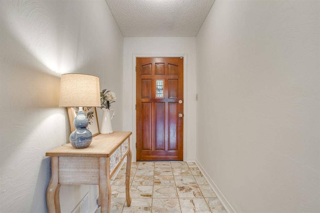 Entryway featuring a wood-panel door with glass inserts and neutral-toned floor tile
