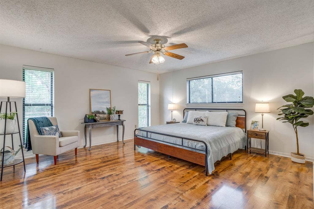 Wood-finish flooring, multiple windows with blinds, ceiling fan, and light-toned walls