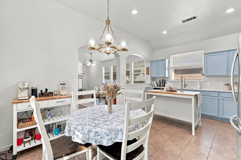 Kitchen featuring light blue cabinetry, white subway tile backsplash, and a gold-toned chandelier