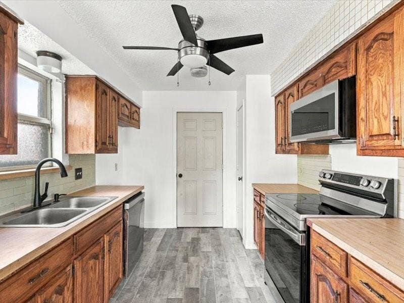725 Southridge Court, Grand Prairie, TX 75052 Kitchen featuring wood-finish cabinetry, stainless steel appliances, a double basin sink with a matte black faucet, wood-finish countertops, and wood-finish flooring
