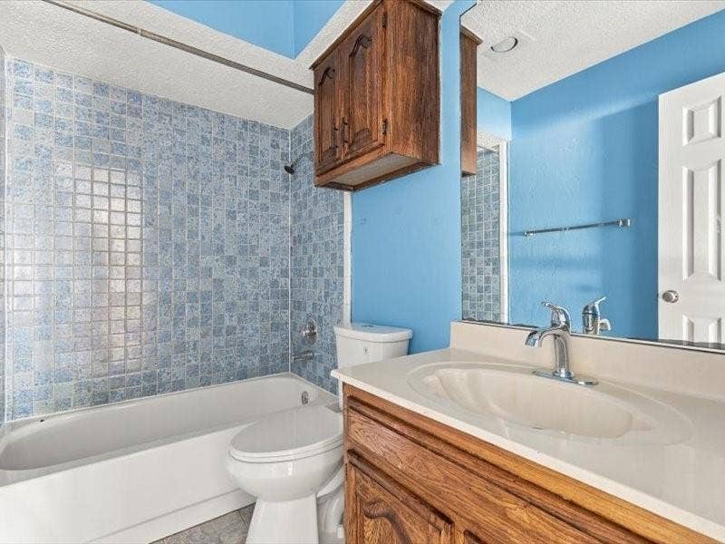 725 Southridge Court, Grand Prairie, TX 75052 Bathroom featuring a tub and shower combination with tiled surround, a vanity with an integrated sink and chrome faucet, and a wall-mounted medicine cabinet