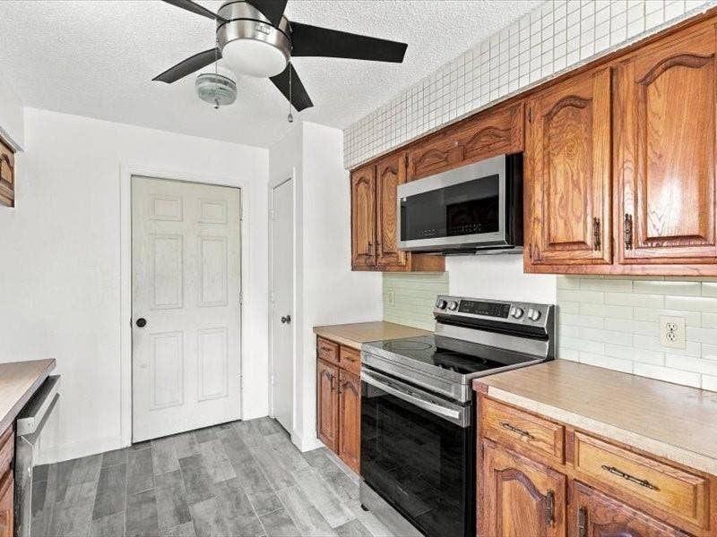 725 Southridge Court, Grand Prairie, TX 75052 Kitchen featuring wood cabinetry, stainless steel appliances, light-toned countertops, and tile flooring