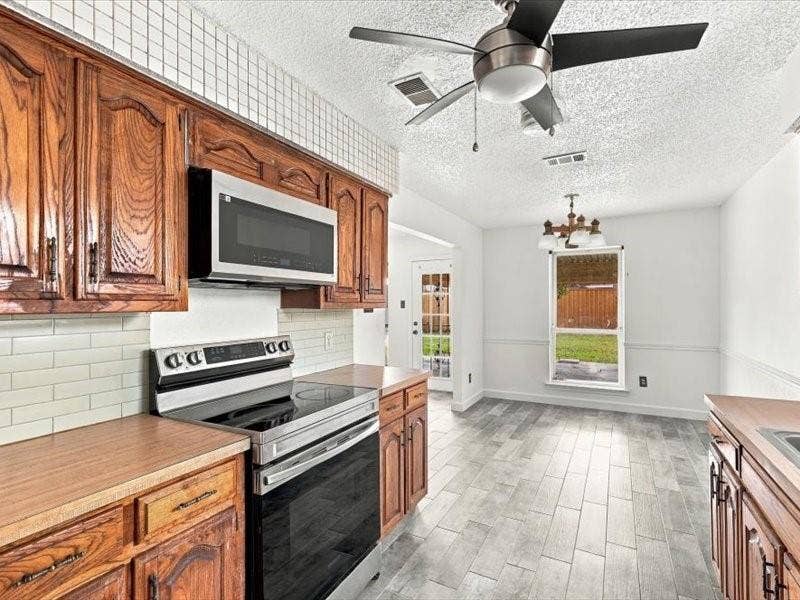 725 Southridge Court, Grand Prairie, TX 75052 Kitchen featuring wood cabinetry, stainless steel microwave, and electric range