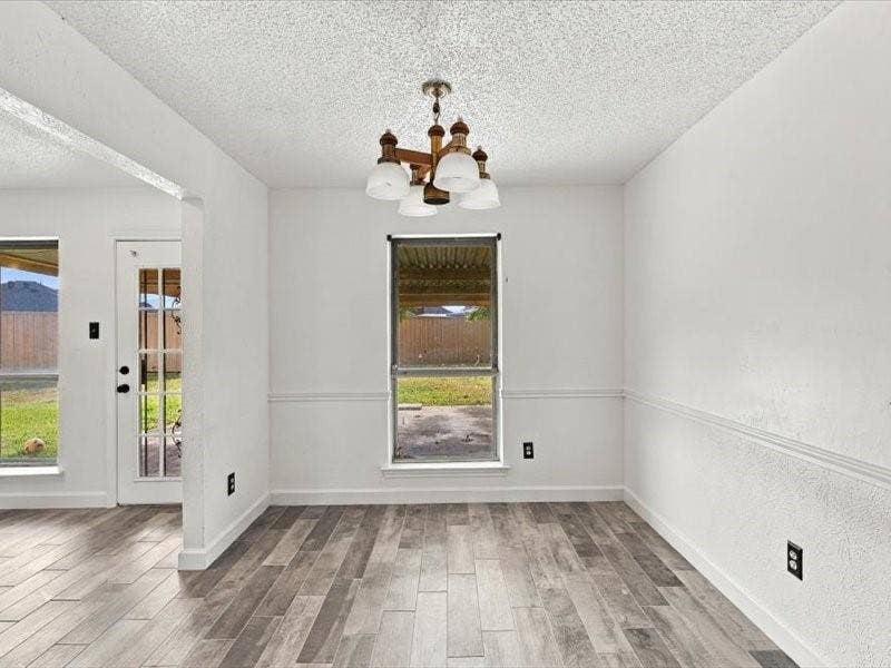 725 Southridge Court, Grand Prairie, TX 75052 Wood-finish flooring with a decorative chandelier, white painted walls with chair rail molding, and multiple windows