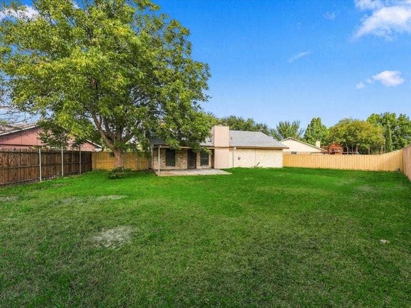 725 Southridge Court, Grand Prairie, TX 75052 Expansive grassy backyard featuring a paved patio and mature trees