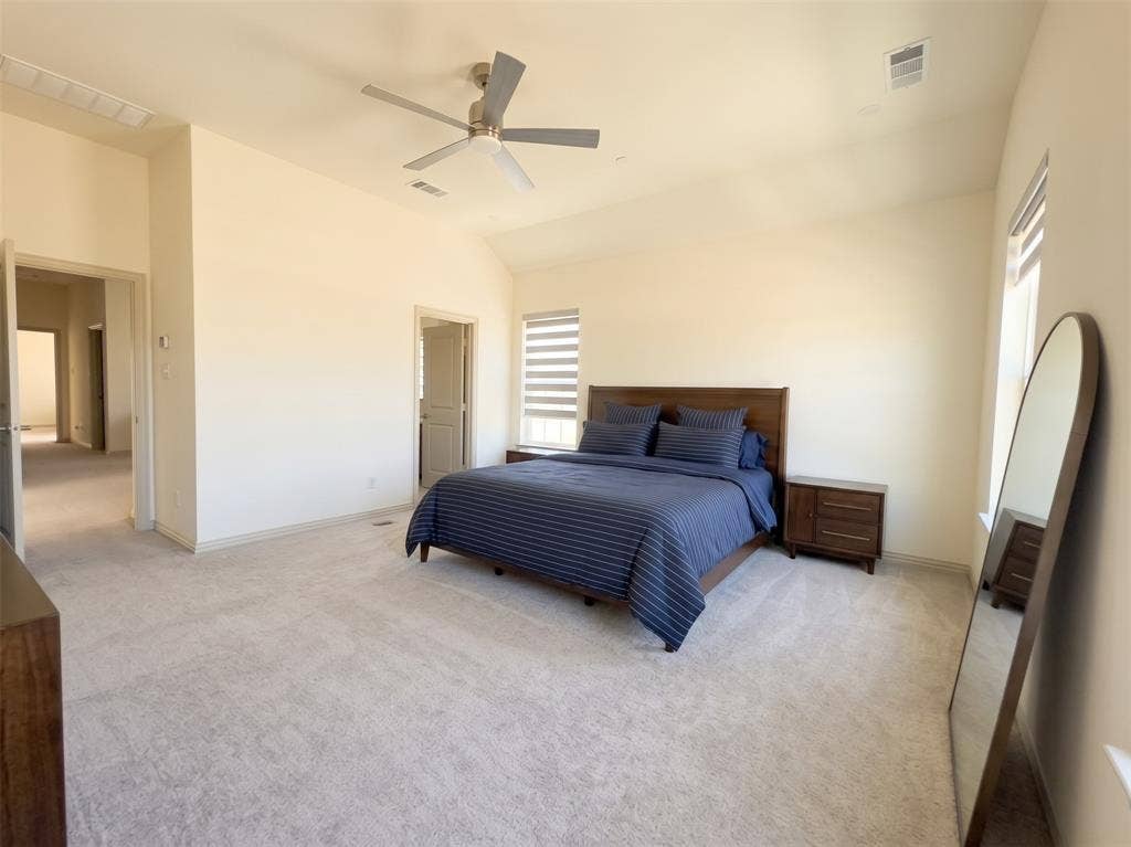 Room with vaulted ceilings, neutral wall tones, carpeted flooring, a ceiling fan, and window treatments with horizontal blinds