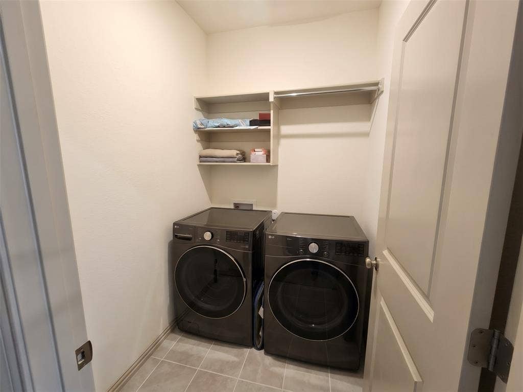 Dedicated laundry area featuring ceramic tile flooring, built-in shelving, and a mounted hanging rod