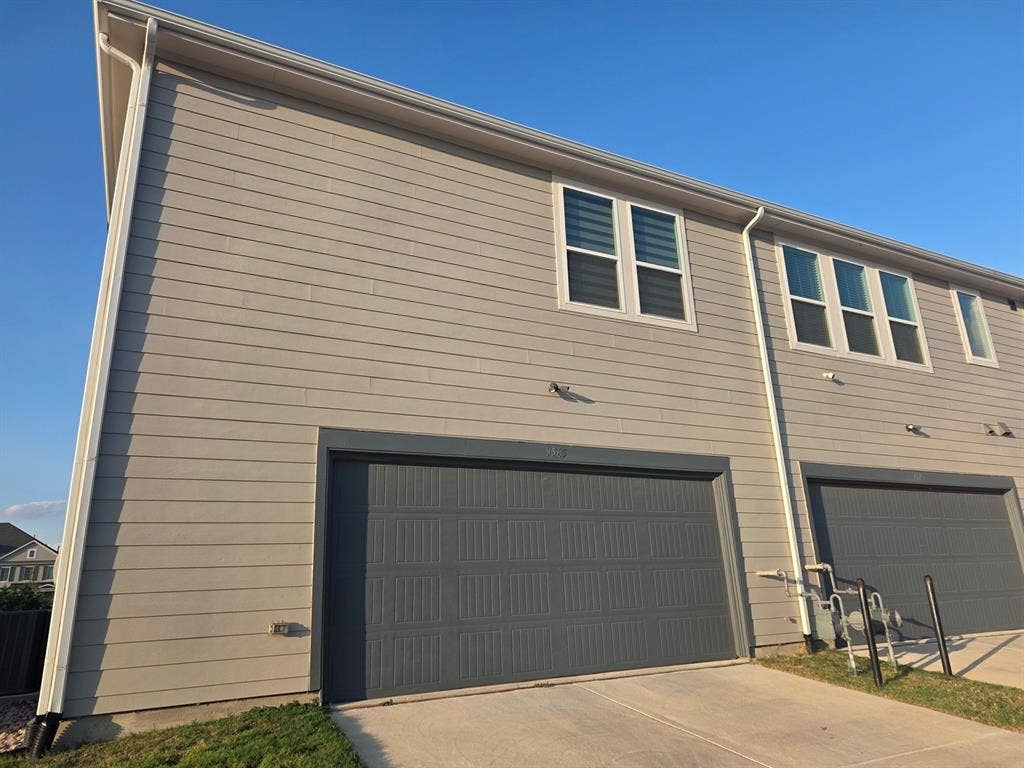 Exterior featuring horizontal siding, a multi-panel garage door, and double-hung windows