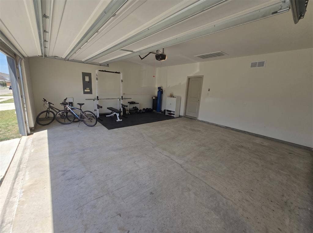Attached multi-car garage featuring a concrete floor, automated overhead door system, ceiling-mounted lighting, and a dedicated water filtration system