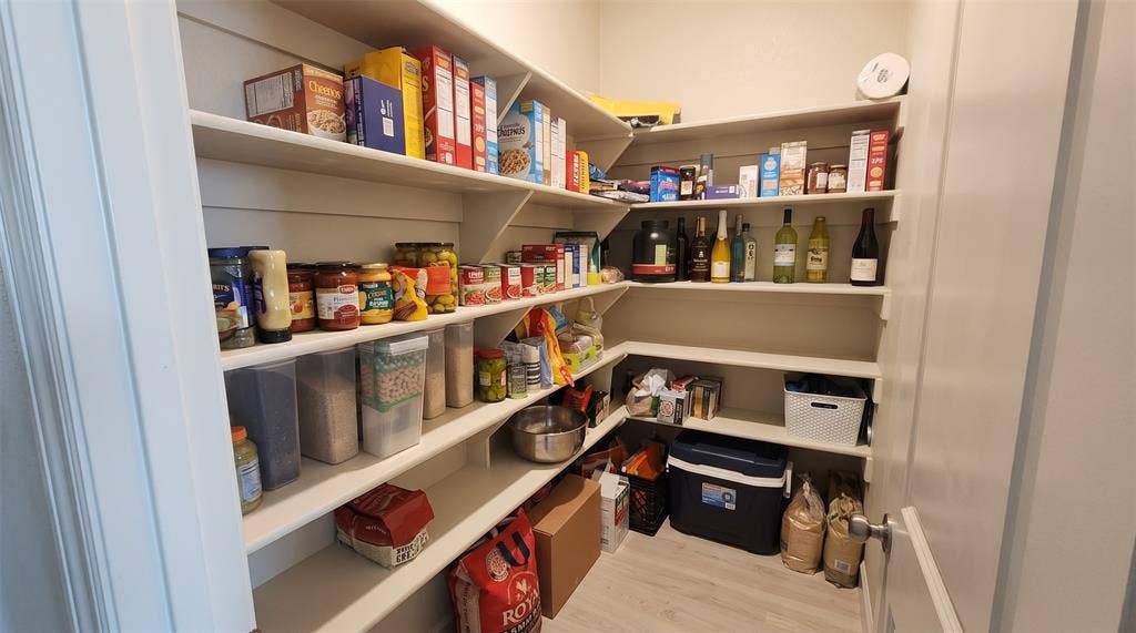 Walk-in pantry featuring white shiplap wall detailing and multiple tiers of built-in wooden shelving