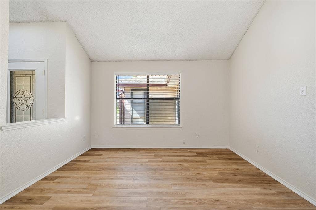 Wood-finish flooring, white walls, and a window with horizontal blinds