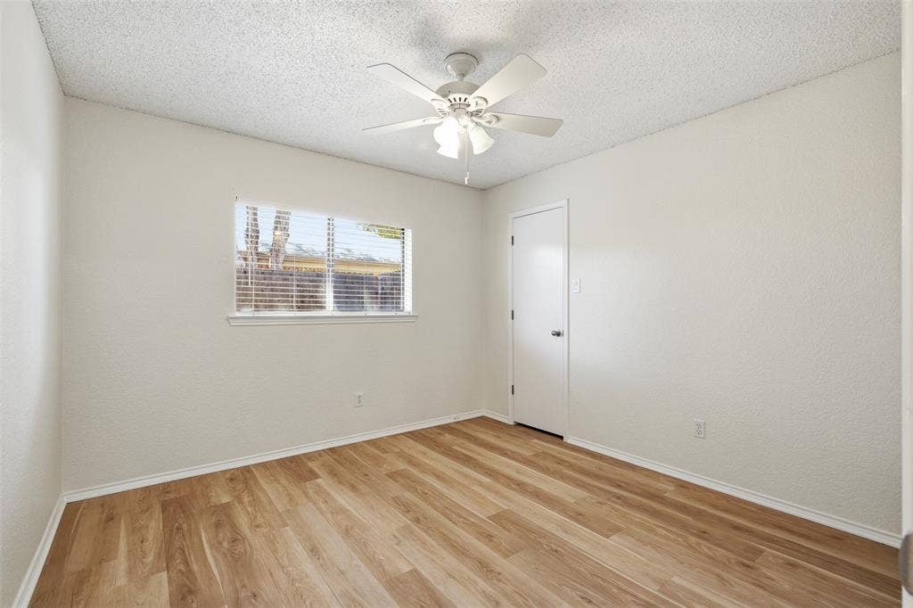 Wood-finish flooring, white walls, and a ceiling fan with integrated lighting
