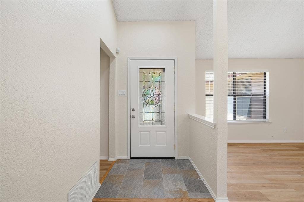 Entryway featuring a decorative glass panel door, slate-look tile flooring, and wood-finish flooring