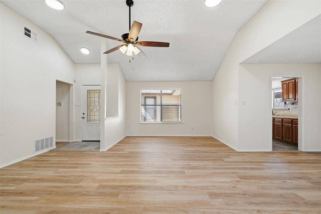 Wood-finish flooring, vaulted ceiling, recessed lighting, ceiling fan, and decorative glass entry door