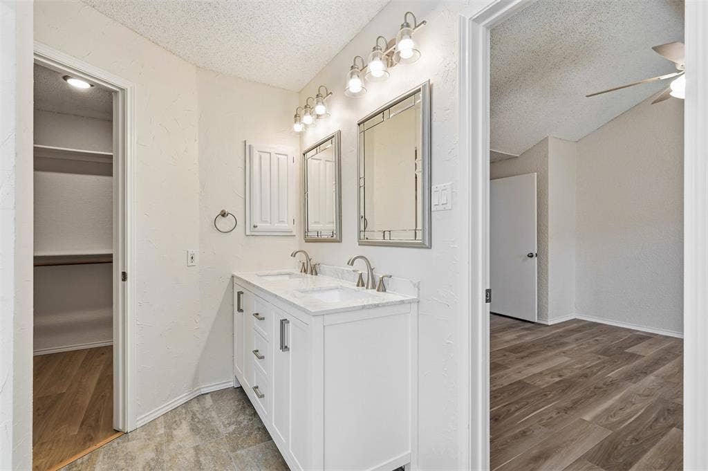 Dual vanity with white cabinetry, integrated sinks, chrome fixtures, and individual framed mirrors
