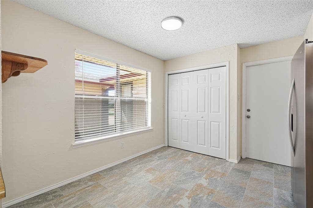 Light-colored walls, window with blinds, bi-fold closet doors, tile flooring, and flush-mount ceiling light