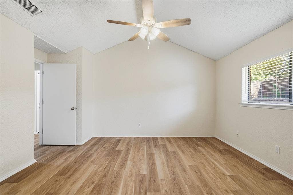 Vaulted ceiling with a ceiling fan, wood-finish flooring, and a window with blinds