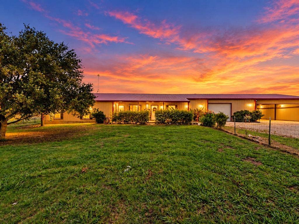 5801 County Road 4128, Scurry, TX 75158 Expansive grassy area with mature trees, red metal roof, covered entry, and attached garage