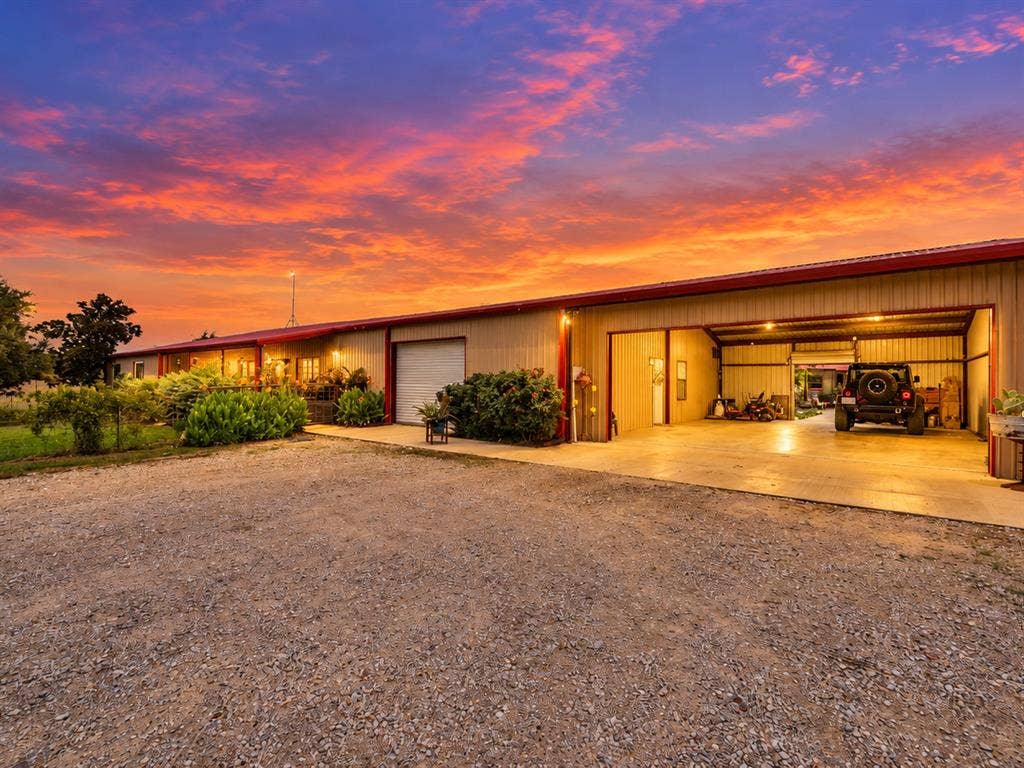 5801 County Road 4128, Scurry, TX 75158 Metal-sided structure with a red roof, featuring a large open bay and an additional garage door