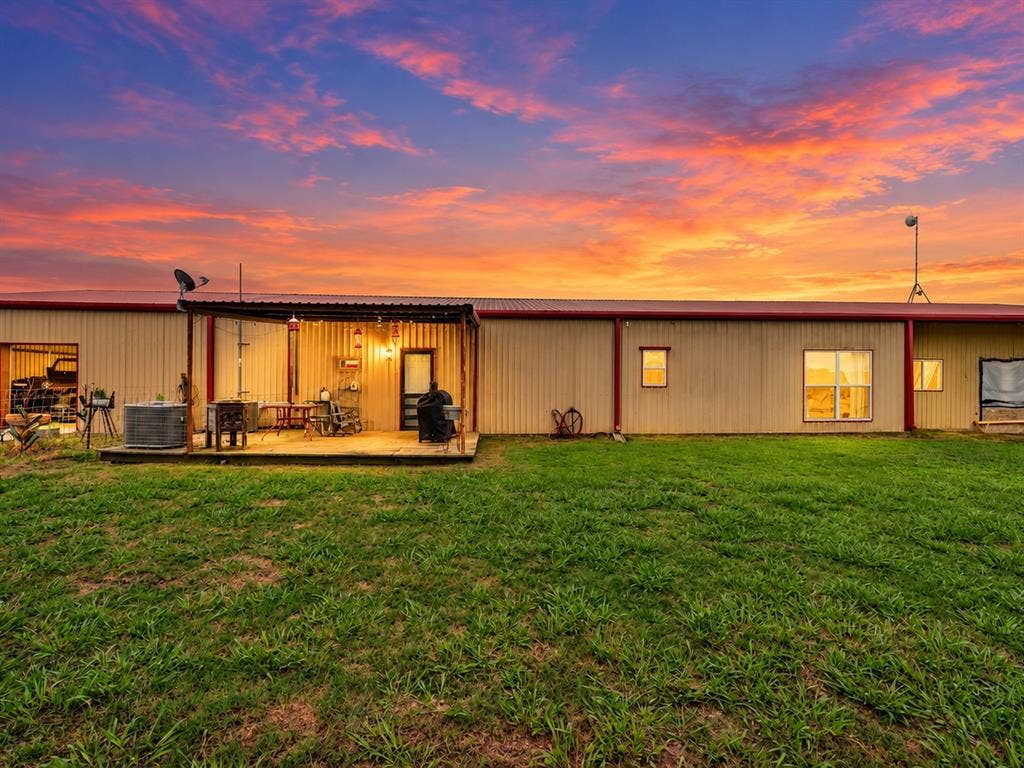 5801 County Road 4128, Scurry, TX 75158 Metal-sided structure with a red trim roof and an integrated wooden deck
