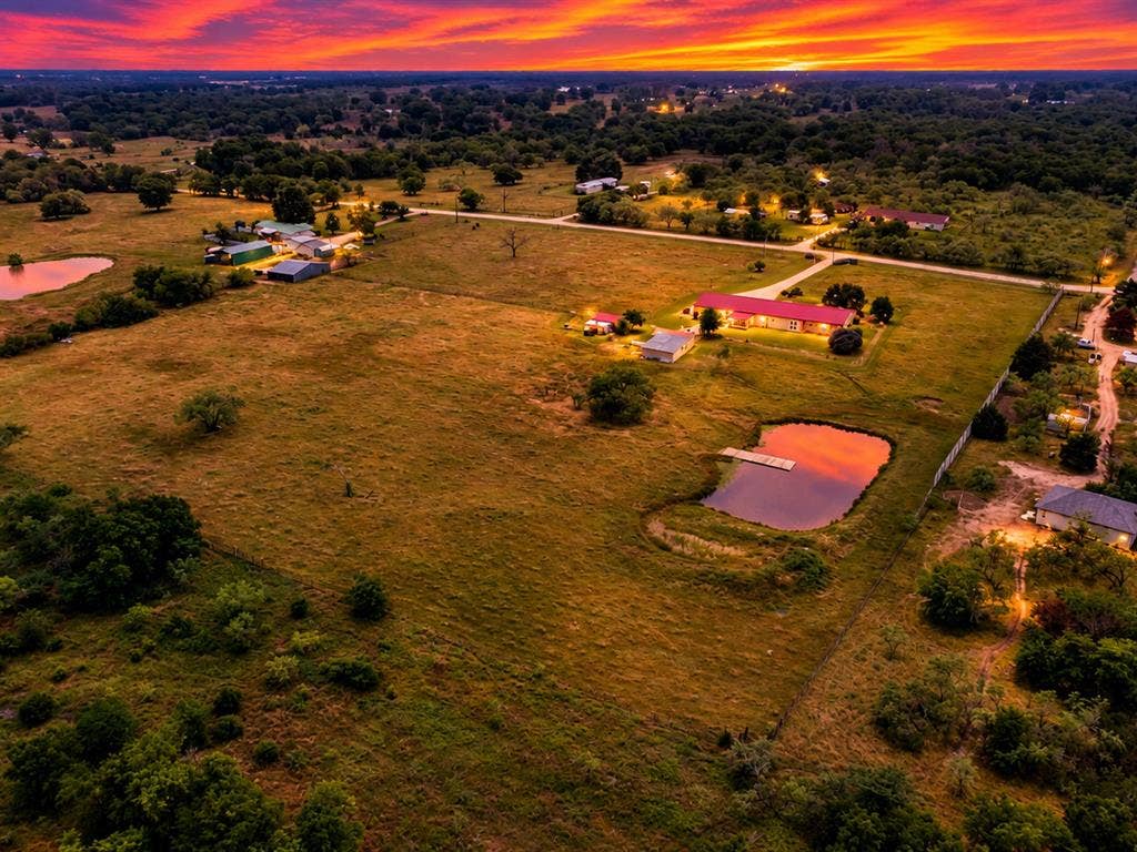 5801 County Road 4128, Scurry, TX 75158 Expansive property featuring a private pond with a dock, multiple outbuildings, and a residence with a red roof
