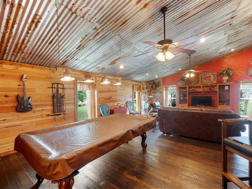 5801 County Road 4128, Scurry, TX 75158 Corrugated metal ceiling, wood-finish flooring, accent wood plank wall, built-in entertainment center, and multiple ceiling fans