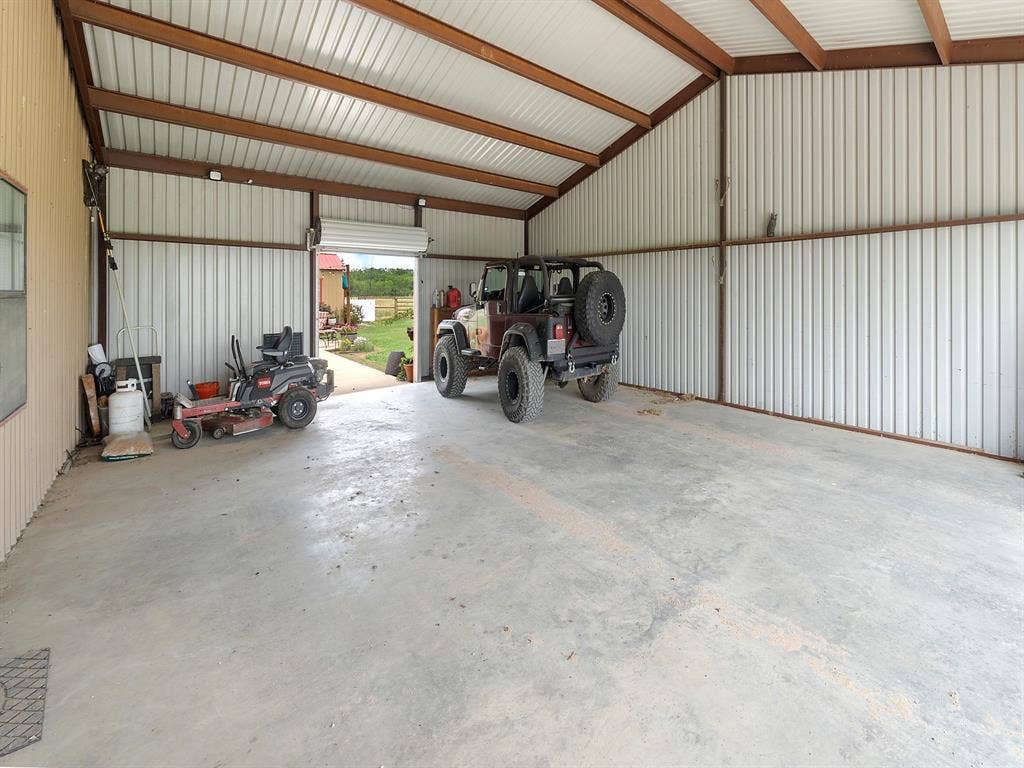 5801 County Road 4128, Scurry, TX 75158 Detached metal-sided workshop featuring a concrete floor, exposed steel beams, vaulted ceiling, and an oversized roll-up garage door