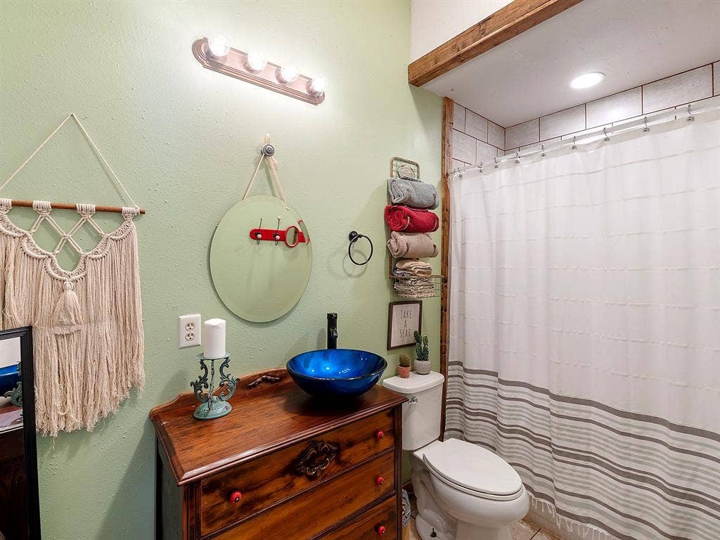 5801 County Road 4128, Scurry, TX 75158 Bathroom vanity featuring a wooden base, blue glass vessel sink, matte black faucet, and a wall-mounted four-light fixture