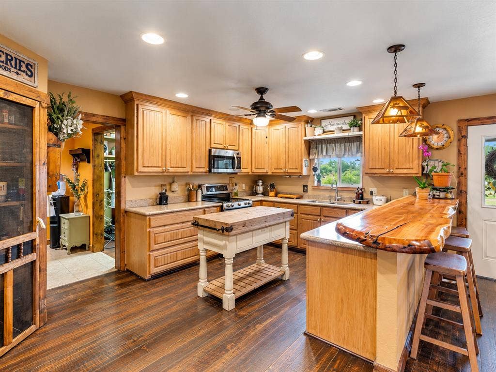 5801 County Road 4128, Scurry, TX 75158 Kitchen featuring wood-finish flooring, recessed lighting, wood cabinetry, stainless steel appliances, and a live-edge wood breakfast bar