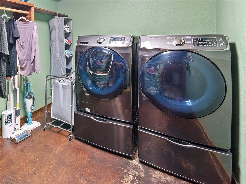 5801 County Road 4128, Scurry, TX 75158 Laundry area featuring front-loading metallic finish washer and dryer with integrated storage pedestals and wall-mounted wooden shelving