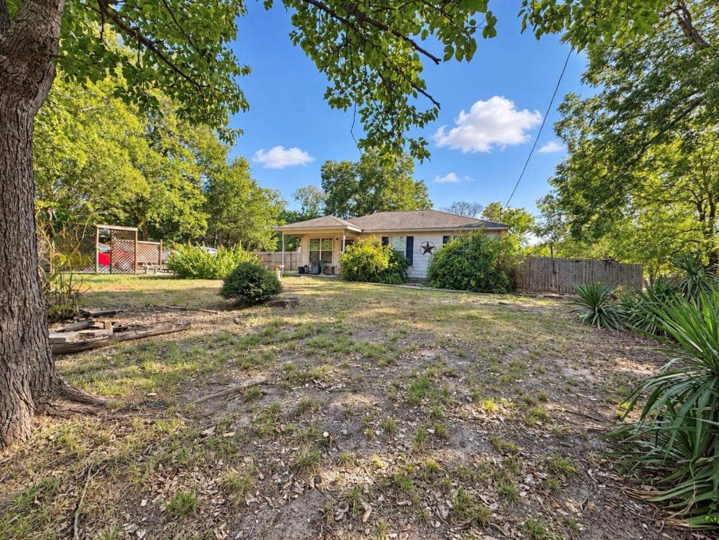 208 Olive Street, Lone Oak, TX 75453 Expansive outdoor area featuring mature trees, a privacy fence, and a single-story residence
