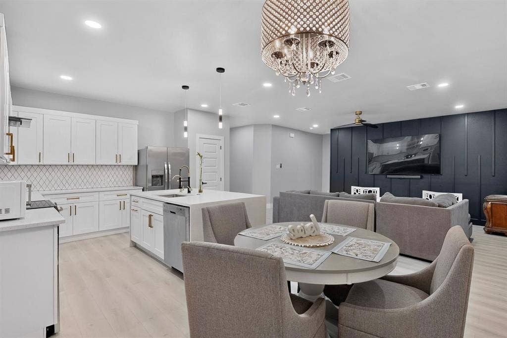 Kitchen featuring white shaker-style cabinetry, a central island with a countertop, wood-finish flooring, recessed lighting, and a dark-toned paneled accent wall